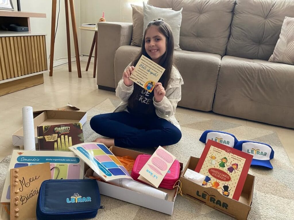 Criança em casa exibindo o Plano Letrar, material pedagógico do projeto Letrar Leitura Infantil